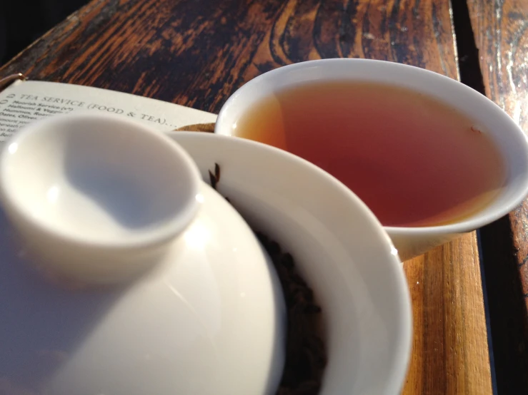 a cup with a saucer sitting on top of it next to an open book