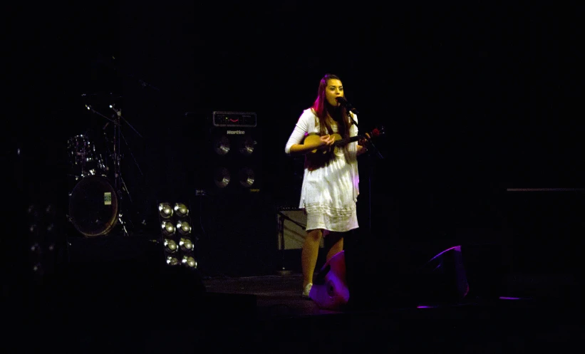 a female on stage playing the guitar in front of her