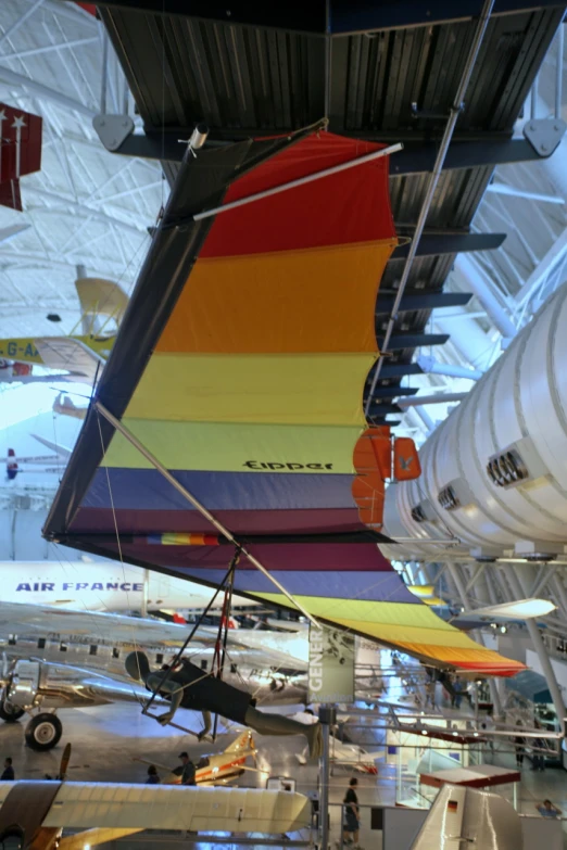 several multi - colored flying airplanes hanging in the air