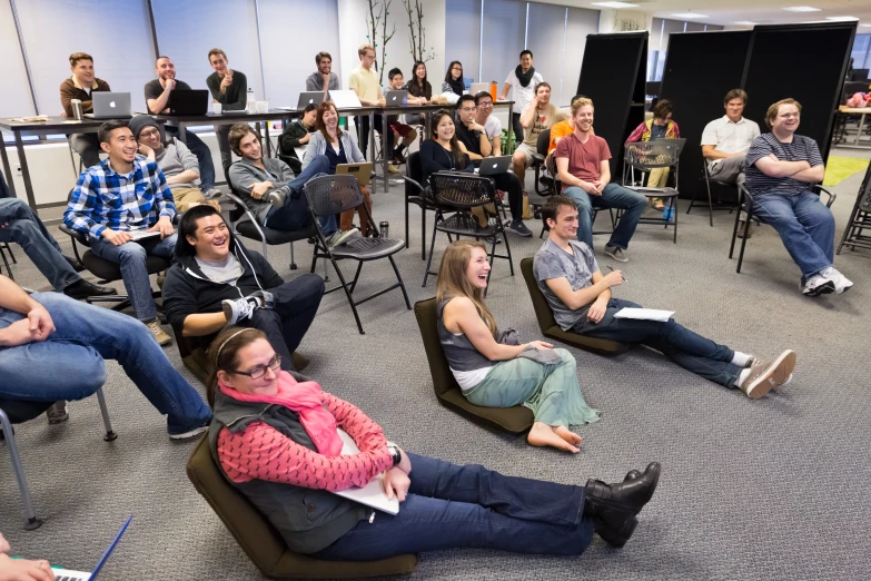 a crowd of people sitting and standing around in chairs