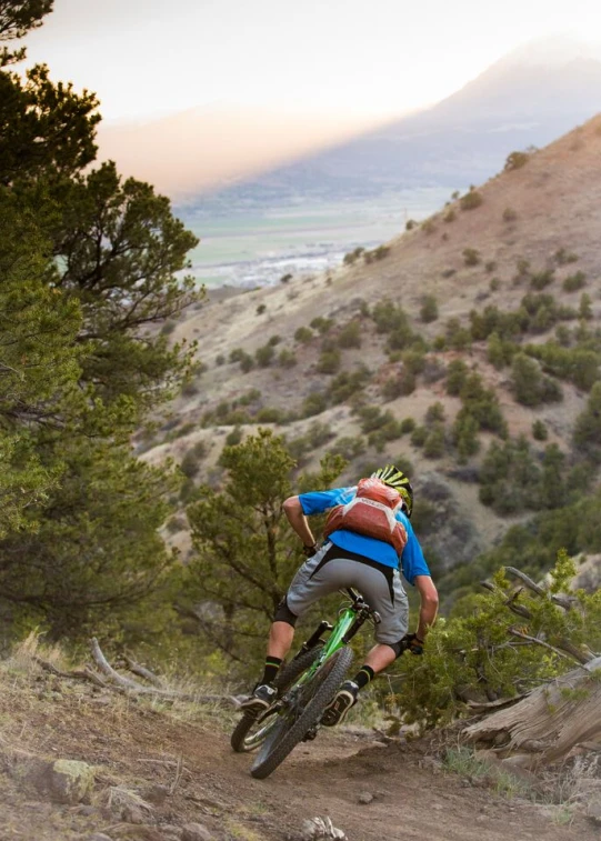 the man in the blue shirt is riding a mountain bike