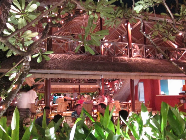 outside, tables with chairs are in front of a red building