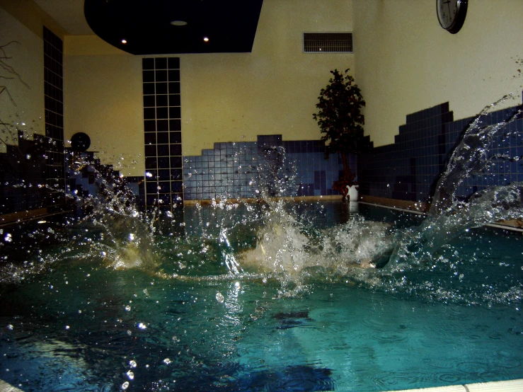 a man is in an indoor swimming pool that has some water coming out