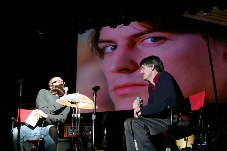 two guys are sitting on a chair talking