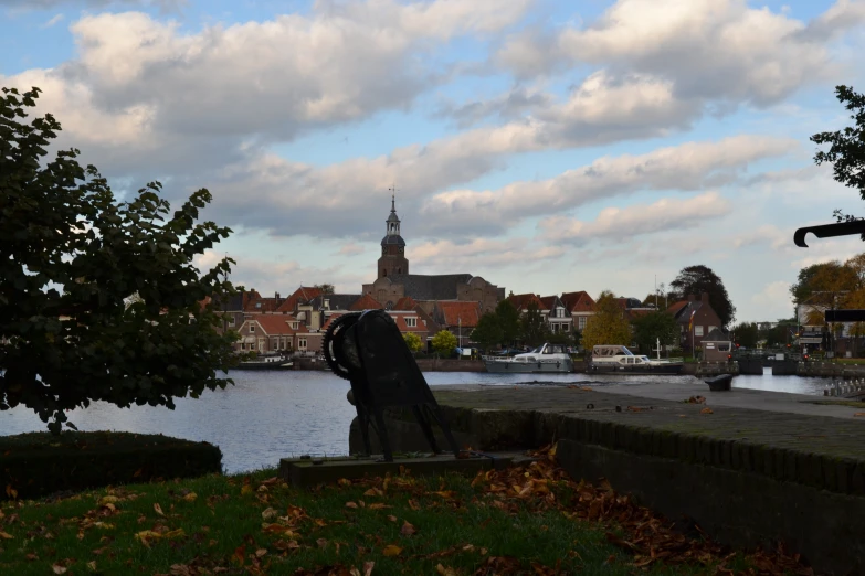 a statue overlooking a river and buildings with a clock tower