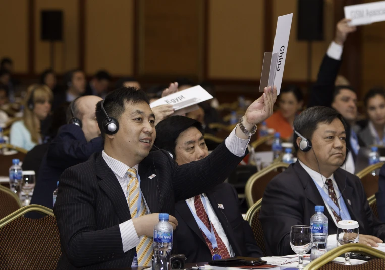 a group of people sitting at tables and one person holding papers