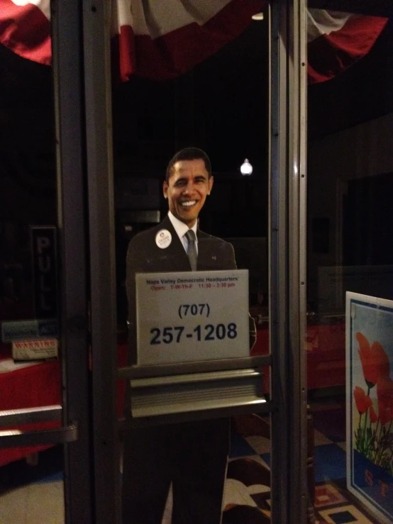 obama standing behind a sign in the middle of a room