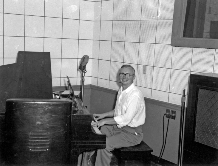 an older man is sitting at a piano in his bathroom