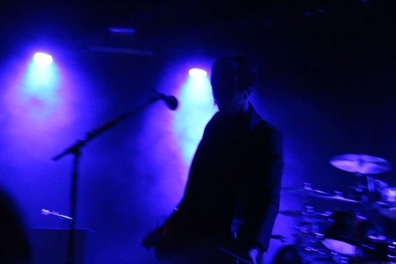 a man with guitar on a stage near some lights