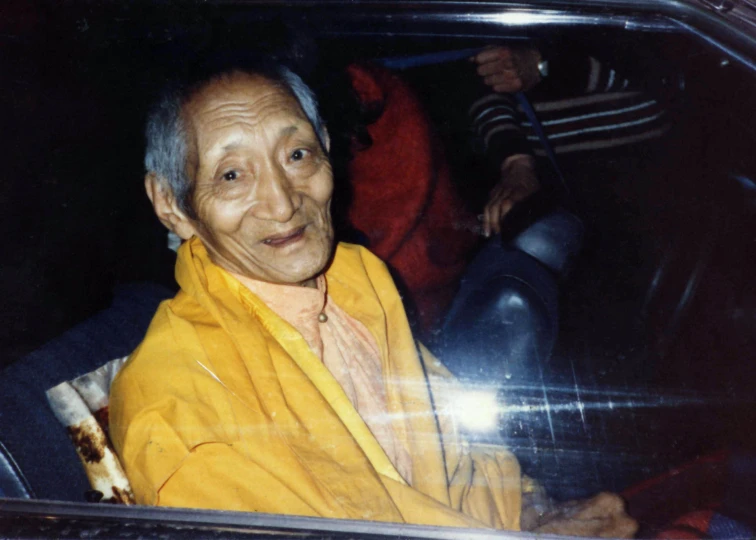 an elderly man smiling sitting in the drivers seat of a car