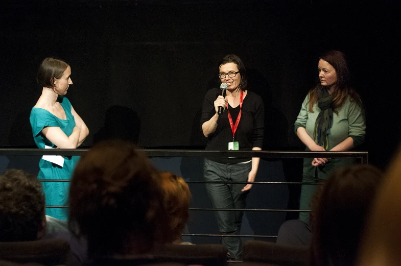 three women are talking on stage with microphones