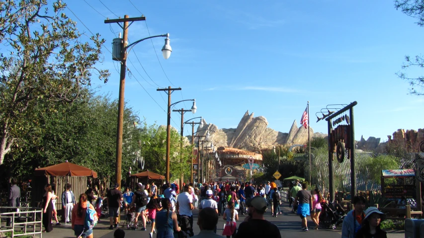 people are walking down a street lined with amut park attractions