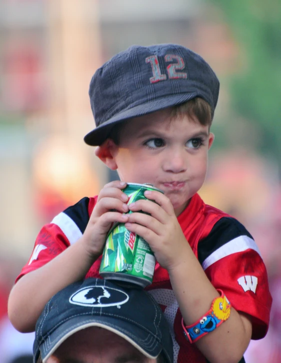a boy wearing a hat and holding a can of soda