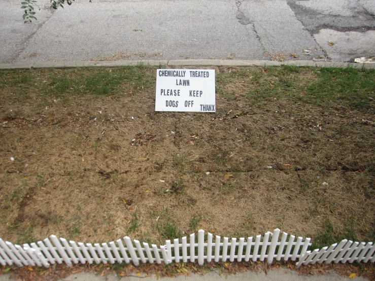 a sign placed in the grass by a fence
