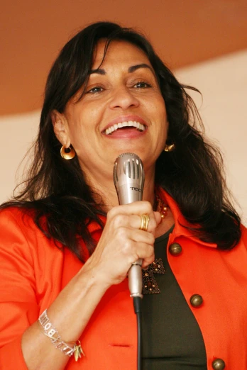 the woman is wearing an orange coat and holding a microphone