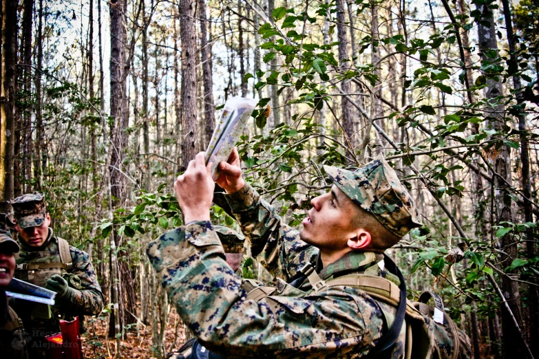 a man in uniform standing in the woods using a cell phone