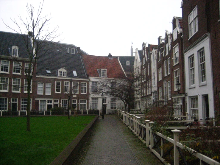 a city street with multiple buildings and a white fence