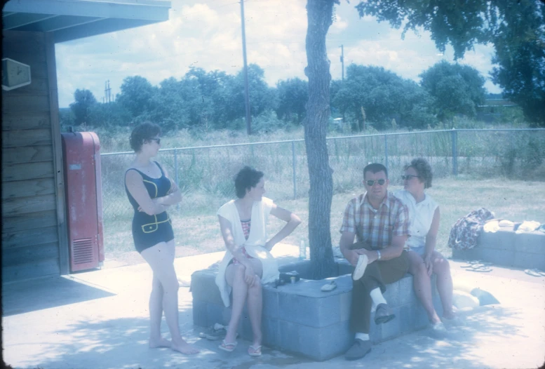 four people sitting around two coolers with a person in a bathing suit on the side