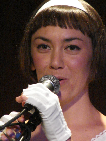 a woman wearing white gloves and holding a microphone