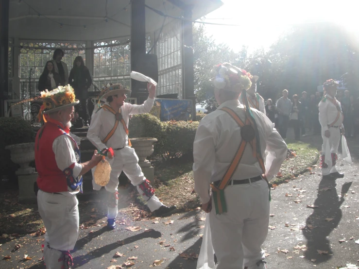 several men in white outfits and orange hats marching down the street