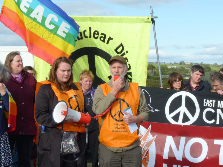 people holding protest signs standing behind a peace sign