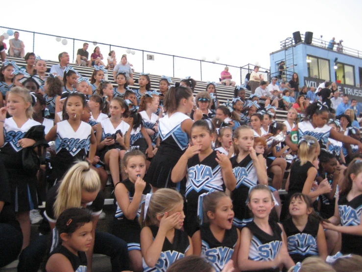 a group of girls in cheer uniforms sitting down