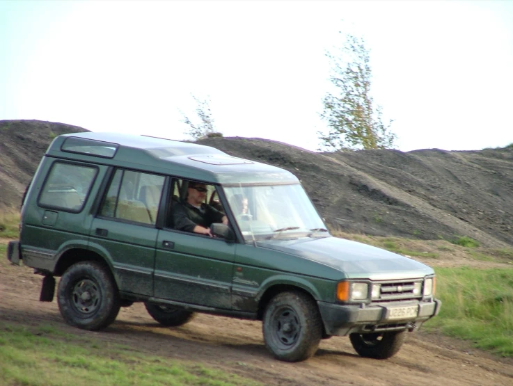 a person sitting inside a green suv going down a dirt road