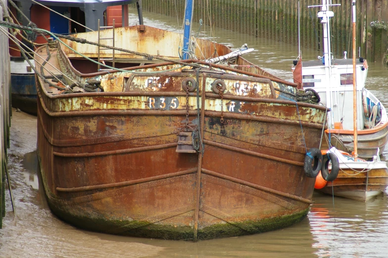 rusted boats docked at the side of a river