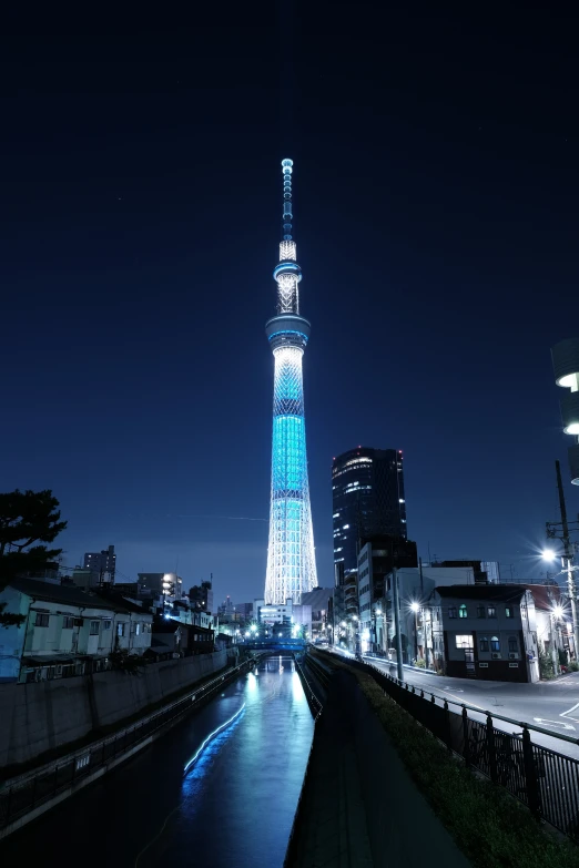 a tower lit up in the night next to a body of water