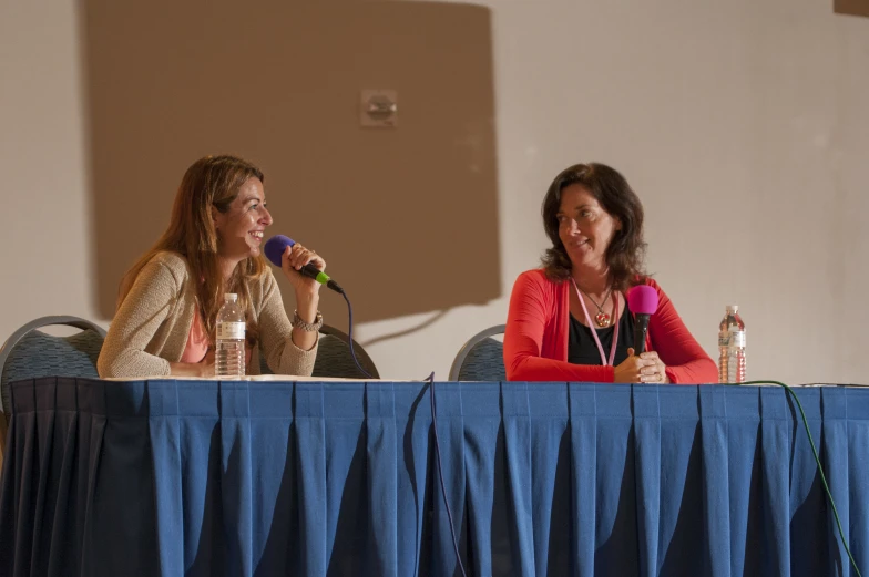 two women are speaking into microphones at a press conference