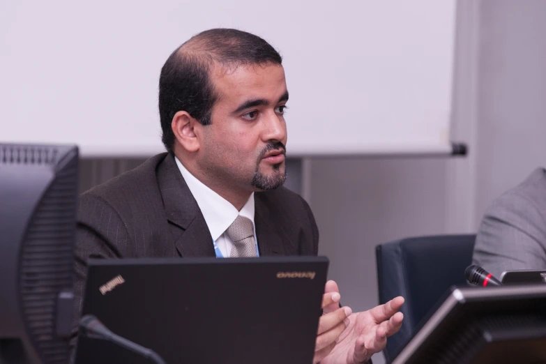 two men in suits are sitting next to each other at a desk