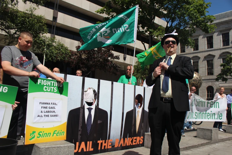 two men are holding flags and standing in front of a protest banner