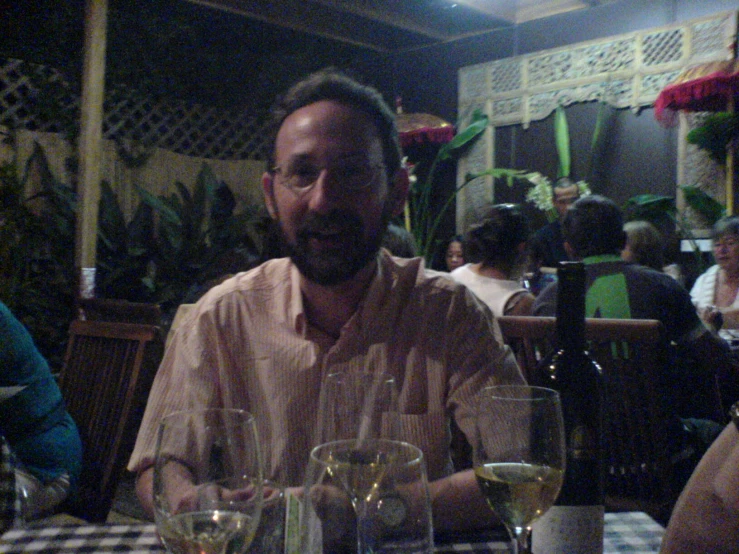 a man sitting at a table with wine glasses