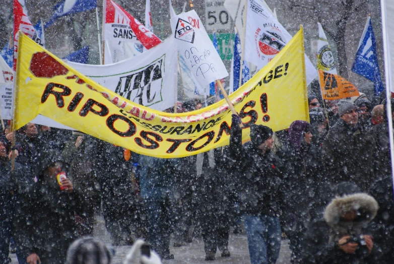 a large protest outside in the snow holding up a yellow banner