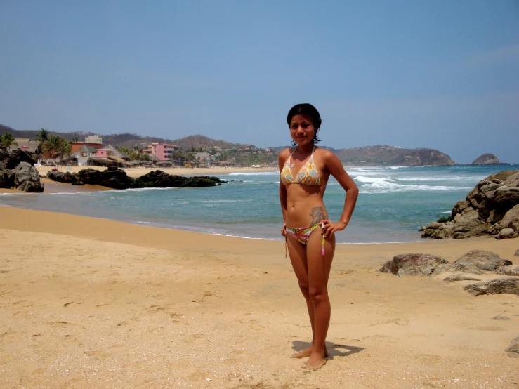 woman standing on the beach with her hands in her pockets