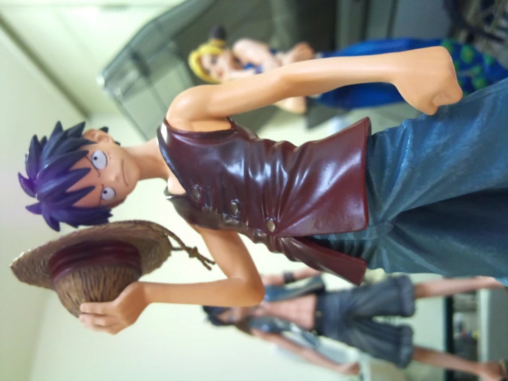a figurine of a boy with purple hair and leather outfit holding a baseball cap and ball