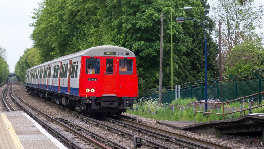 red and silver train passing through train yard