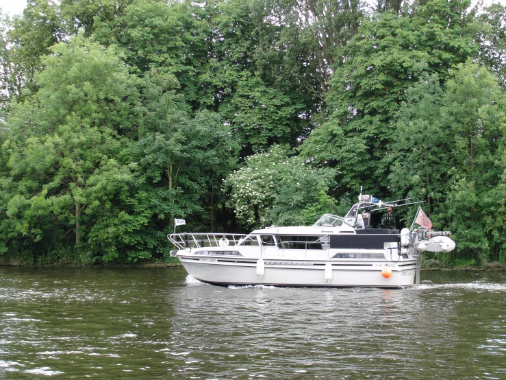 there is a boat traveling on the water next to some trees