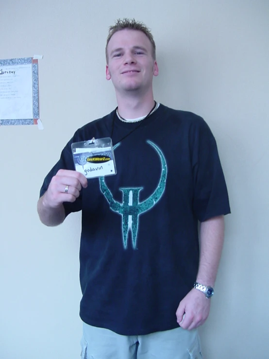 a guy holds up a white business card and wears blue shirt