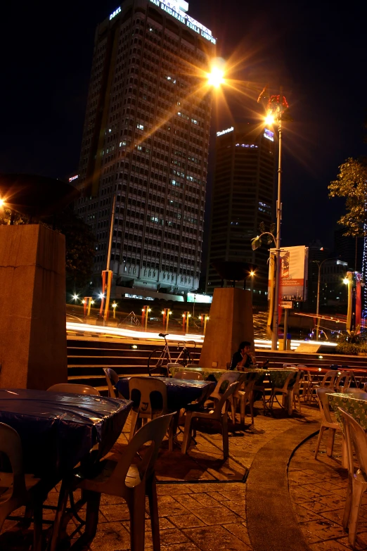 the dark lit city street has many tables and chairs set out outside