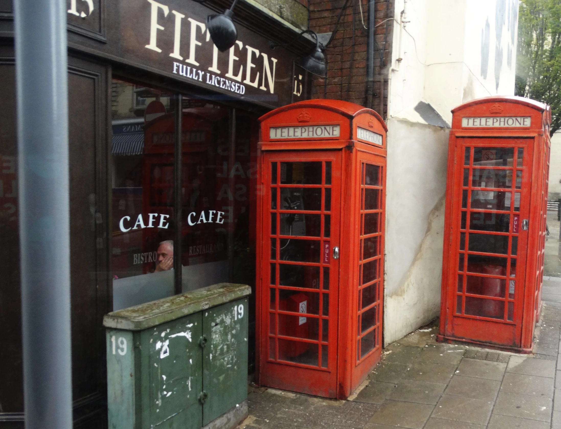 a street scene with two phone booths and an empty garbage can