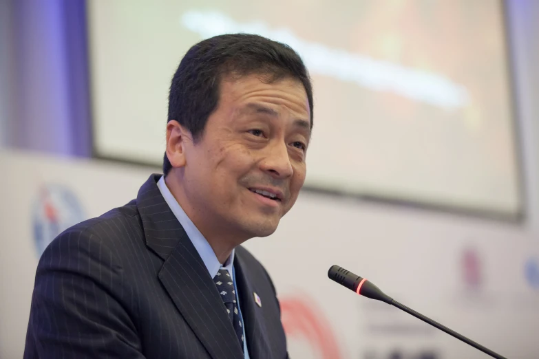 a man in suit and tie making a speech at a podium