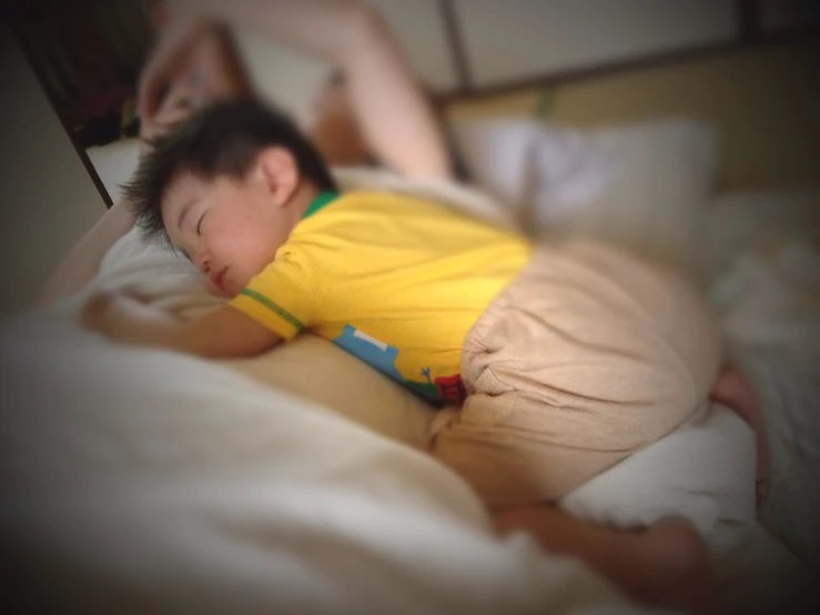 a child wearing yellow laying on top of a bed