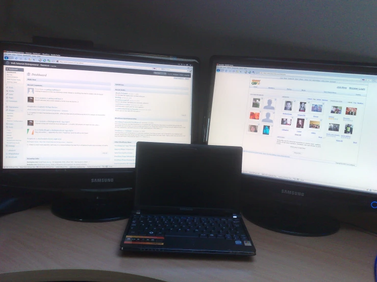 a laptop computer sitting next to two monitors