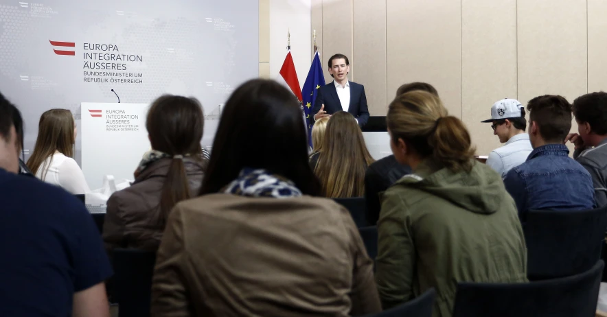 a man standing in front of a crowd in front of flags