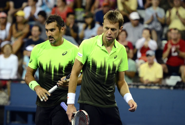 two tennis players stand side by side on a court with people in the background