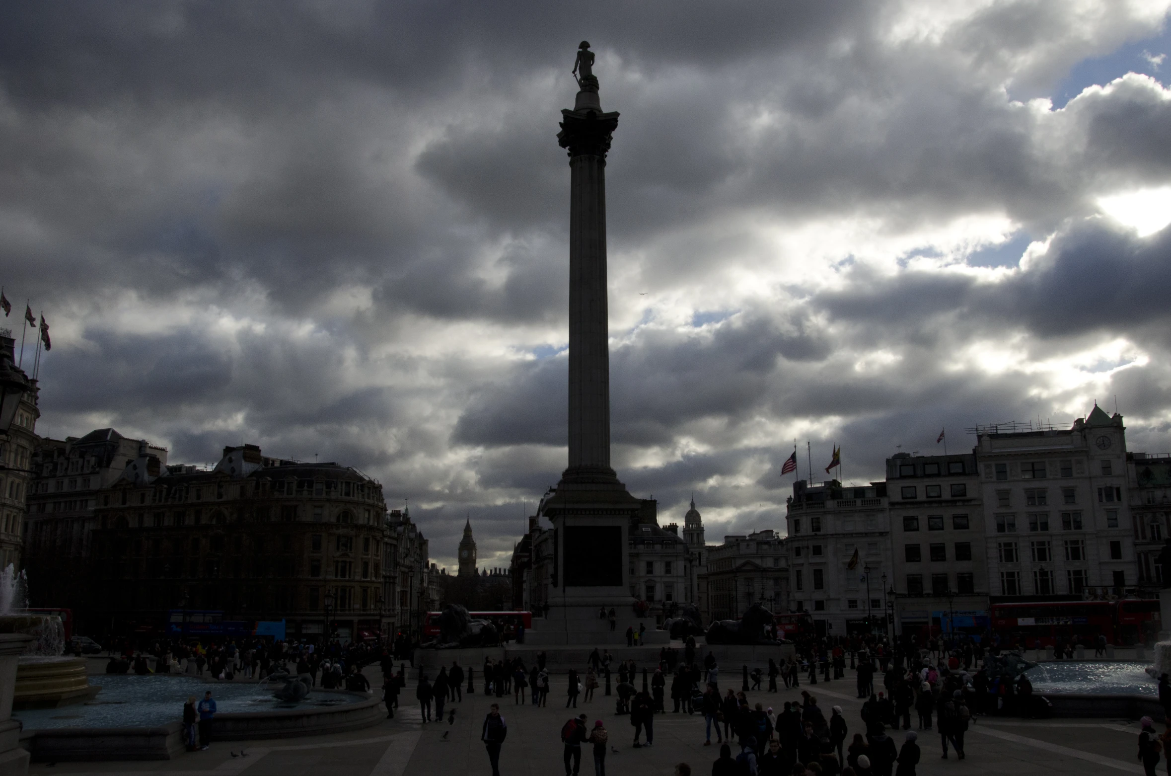 the statue sits near the buildings under a dark sky