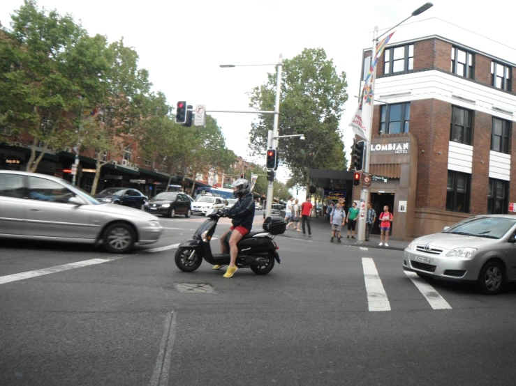 a couple of people sitting on motor bikes crossing a busy street