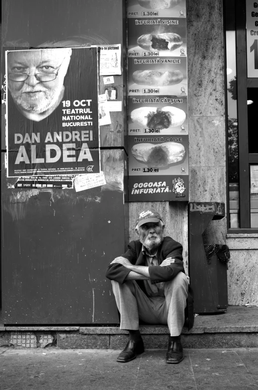 man sitting on curb with his legs crossed in front of advertit