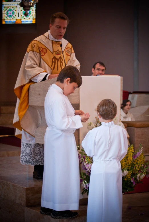 a boy in a white monk outfit getting a medal